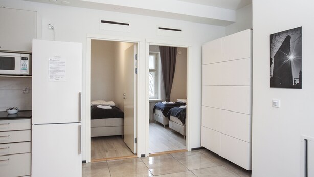 A compact kitchen with a refrigerator, microwave, and a small dining area. - Premium 4-Bedroom Stay in Central Helsinki (Helsinki)