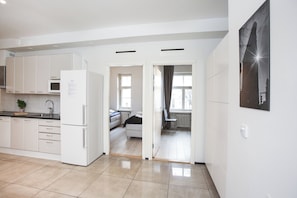 A modern kitchen with white cabinets, a refrigerator, and a dining area with a table and chairs.