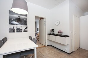 Une cuisine moderne avec des meubles blancs, une machine à café et une horloge au mur.