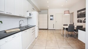 A modern kitchen with white cabinets, a black countertop, and a dining area with a table and chairs. - Premium 4-Bedroom Stay in Central Helsinki (Helsinki)