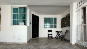A spacious room with a tiled floor, a black door, a window with curtains, and a small table with chairs. - Peaceful 2-bedroom house with AC in charming Santa Marta, WIFI, Tayrona. (Santa Marta)