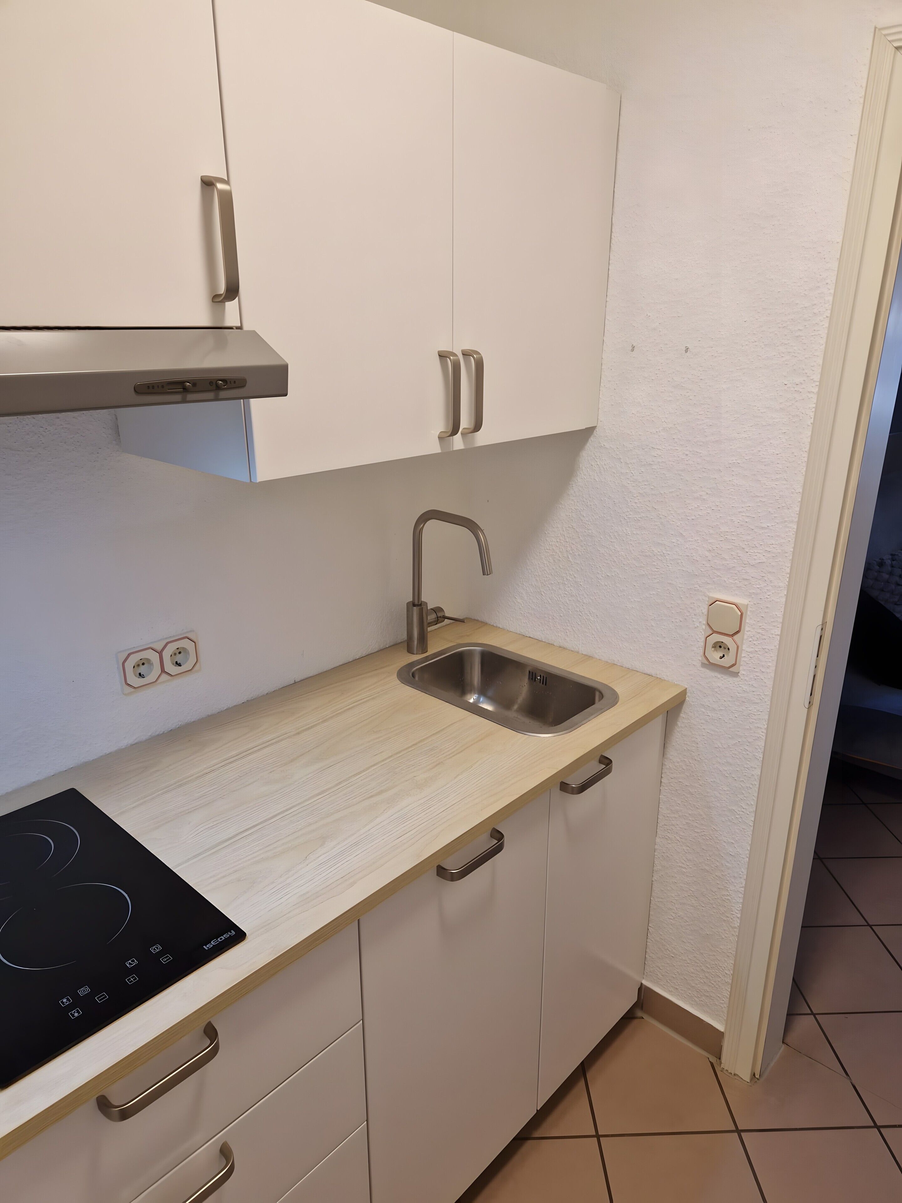 A compact kitchen with a built-in stove, a sink, and cabinets.