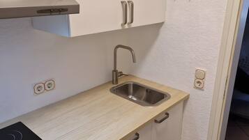 A compact kitchen with a built-in stove, a sink, and cabinets.