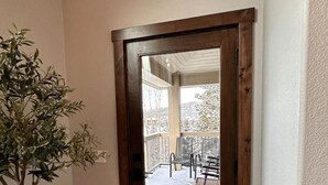 Eine Holztür, die zu einem überdachten Außenbereich mit Terrasse und Sitzgelegenheiten führt.