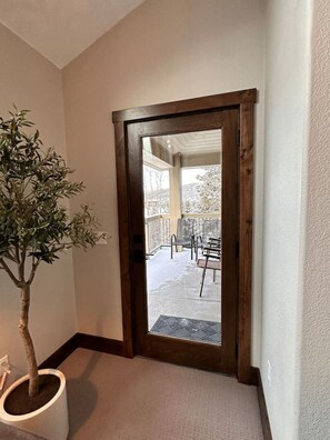 A wooden door leading to a covered outdoor area with a patio and chairs. - Remodeled Condo, Ski in/out with Hot Tub, Spa, Gym (Breckenridge)