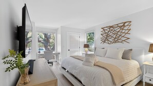 A bedroom with a bed, bedside tables, a TV, and a window. - Seaside Hideaway - Beach Front Luxury! (Johns Island)