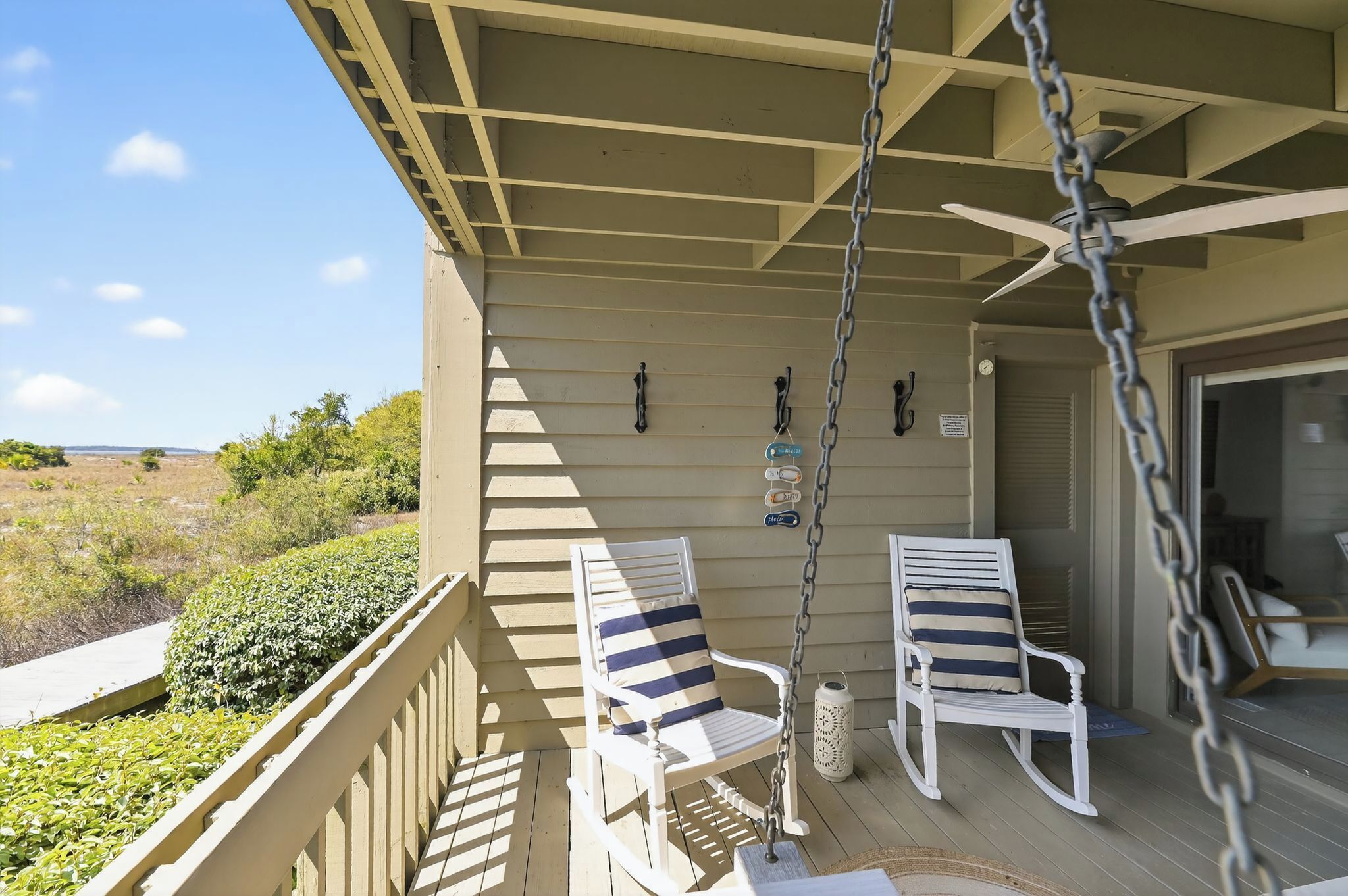 A porch with two rocking chairs, a ceiling fan, and a view of the landscape.