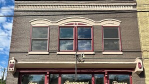 Un edificio de dos pisos con una puerta roja y ventanas, identificado como 'Inn Restaurant Tavern'.