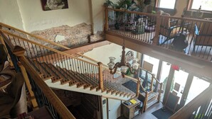 Un interior de varios niveles con una escalera, un comedor y vistas al exterior.