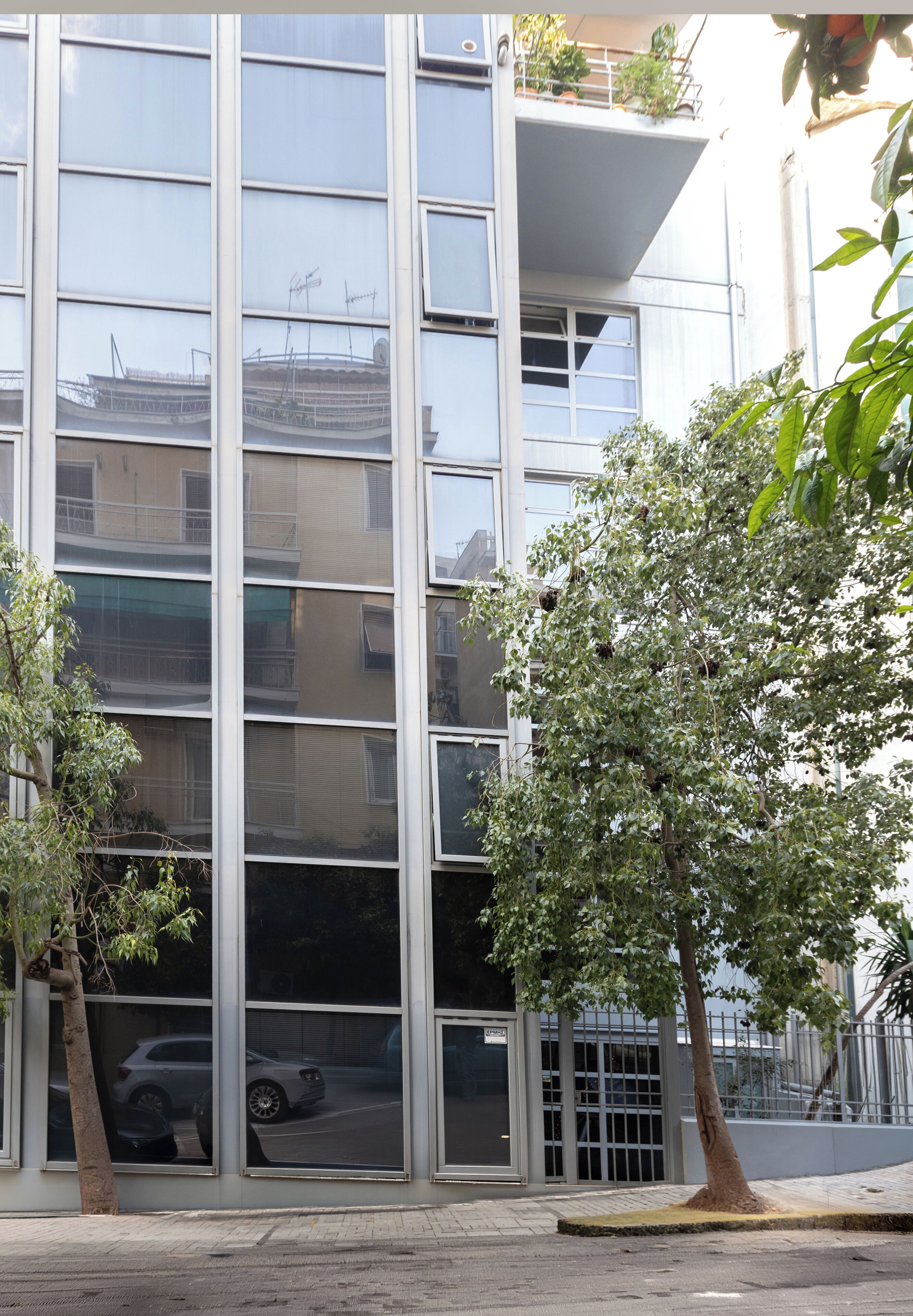 A multi-story building with large windows and a tree in the foreground.
