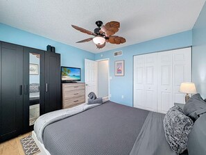 A bedroom with a bed, a ceiling fan, a TV, and a wardrobe. - Harbor House 26 (Treasure Island)