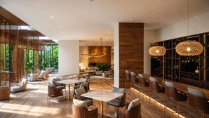 A modern interior with a bar area, seating arrangements, and a view of greenery outside. - Reserva del Mar II Apartment - Cantamar SOHO -383A (Santa Marta)