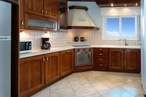 Una cocina con armarios de madera, horno empotrado, microondas y ventana con vista al cielo.