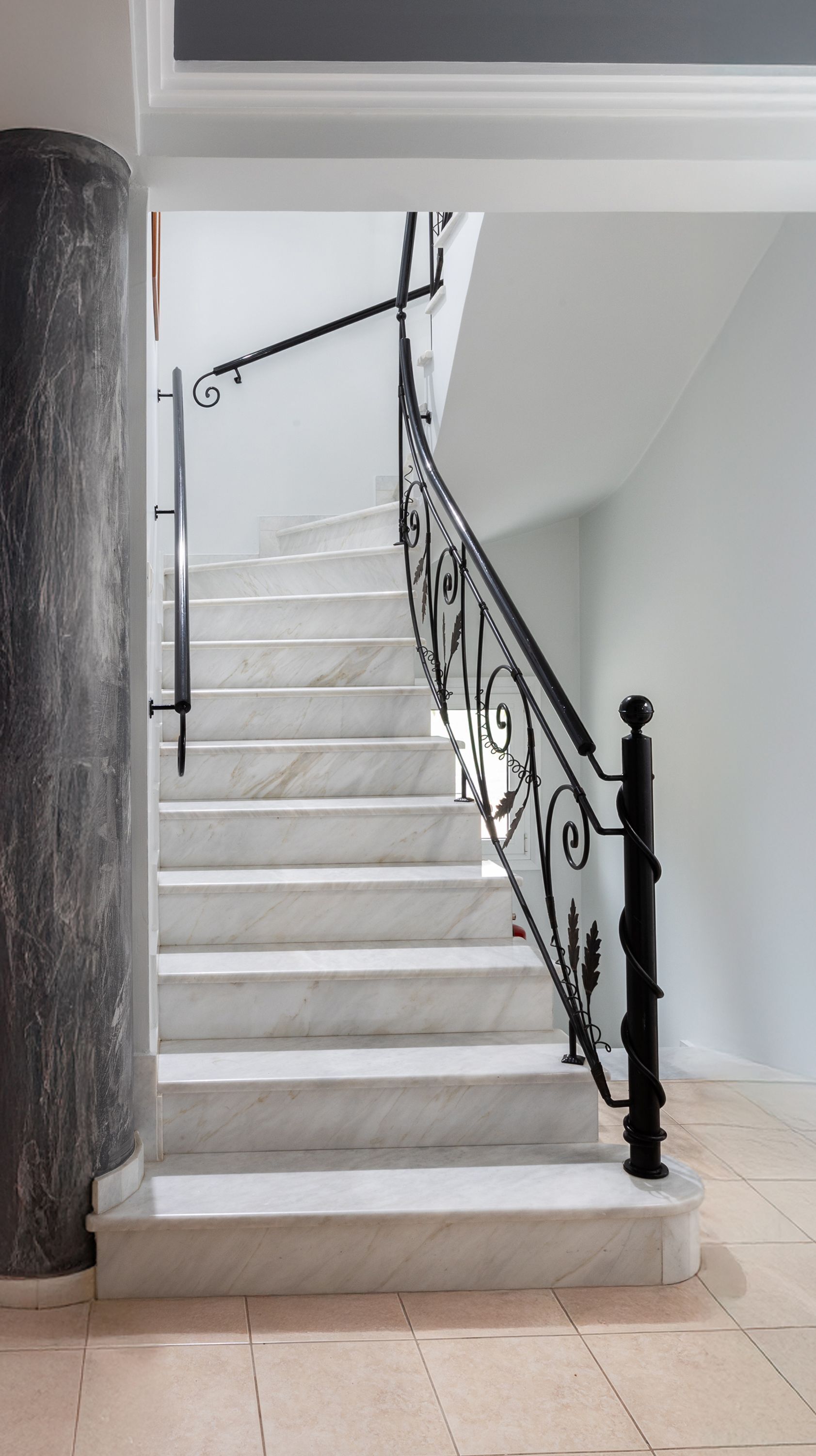 Eine Treppe mit weißen Marmorstufen und schwarzen Metallgeländern.