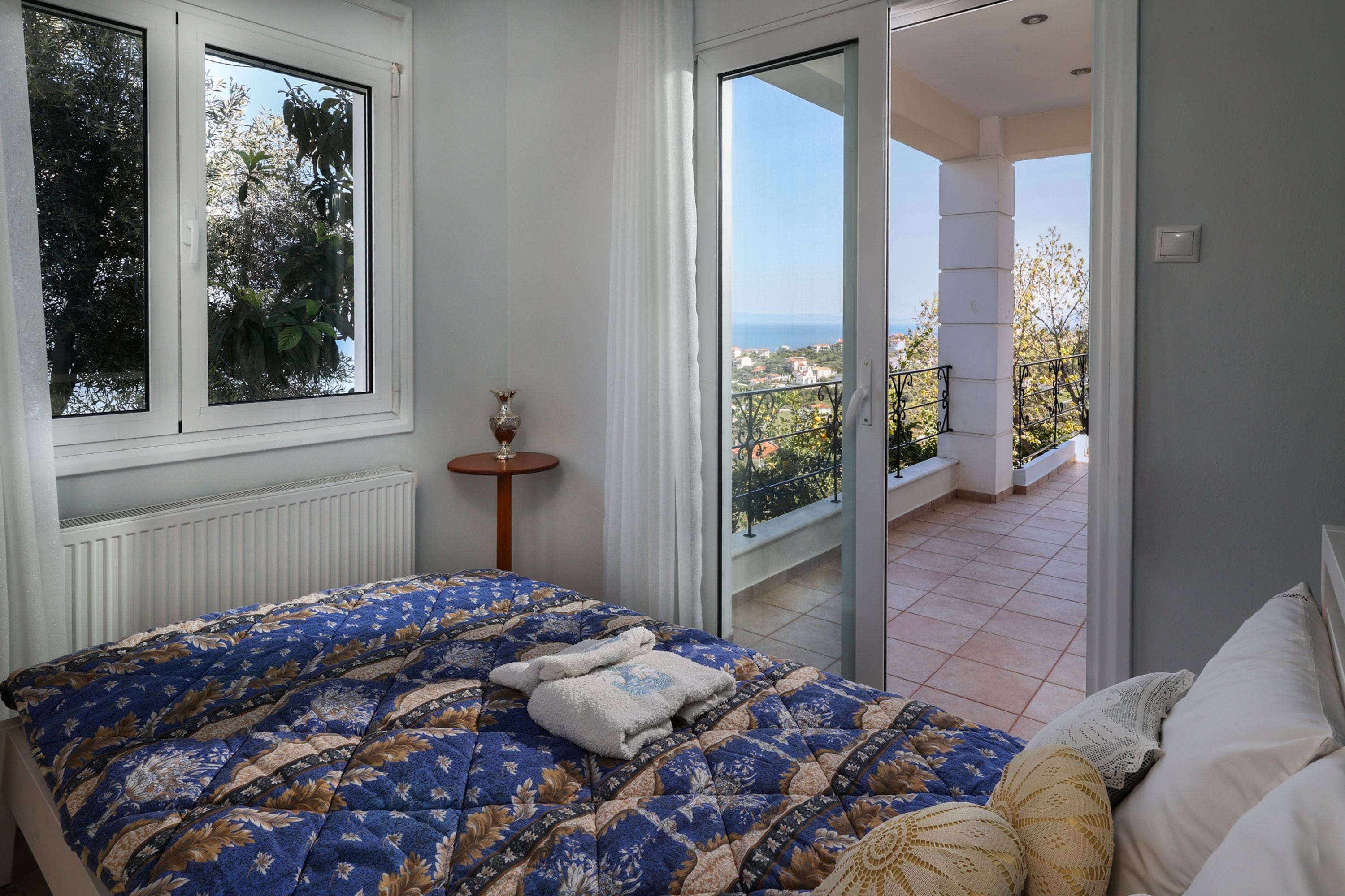 A bedroom with a large bed, a view of the outdoors, and a balcony.