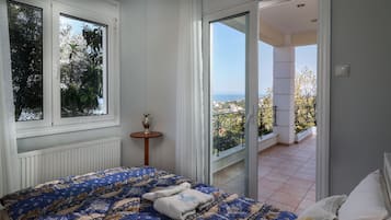 A bedroom with a large bed, a view of the outdoors, and a balcony.