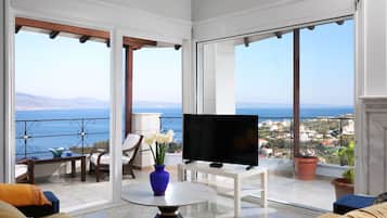 A balcony with a TV, seating, and a view of the sea.