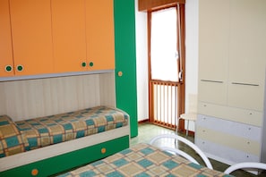 A room with a bed, a chair, a wardrobe, and a window. - Equipped Flat With Garden and Pool (Lignano Sabbiadoro)