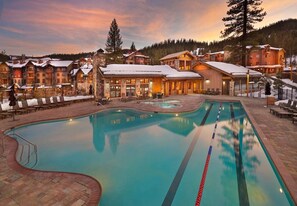 Ein Resort mit Swimmingpool, Liegestühlen und Gebäuden mit schneebedeckten Dächern.
