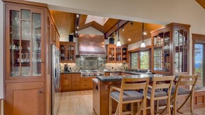 Une cuisine spacieuse avec des meubles en bois, un îlot central doté de chaises et une vue par la fenêtre.