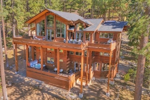 Une cabane en bois à plusieurs niveaux, dotée d’une terrasse, de grandes fenêtres et d’un chemin en pierre.