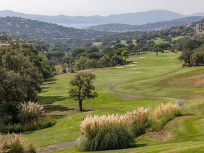 A golf course with a winding path, trees, and a distant view of a town. - Le Palais de la Mer by Interhome (Sainte Maxime)