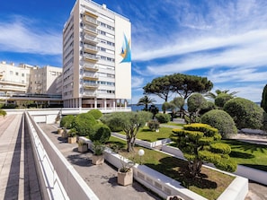 A modern building with balconies, a well-maintained garden with various shrubs and trees, and a clear blue sky. - Le Palais de la Mer by Interhome (Sainte Maxime)