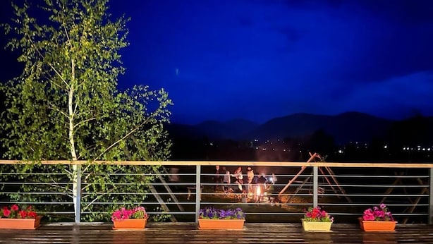 A wooden deck with potted plants and a metal railing overlooking a mountainous landscape. - Kemin Guest House (Kaindy)