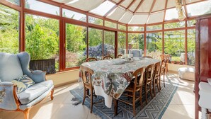 Ein Wintergarten mit Esstisch, Stühlen und einer Couch.