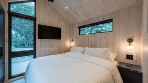 Ein Schlafzimmer mit einem großen Bett, zwei Fenstern und Wandleuchten.