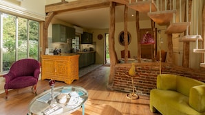 Un vaste espace de vie agrémenté d’un escalier en bois, d’une table à manger et d’une cuisine située au fond de la pièce.