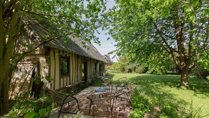 A rustic building with a sloped roof, surrounded by lush greenery and a well-maintained lawn. - La Maison des Mésanges: Private Terrace, Wi-Fi, Reversible Heat Pump, Artist's Garden (La Chapelle-sur-Dun)