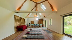A spacious room with a high ceiling, wooden beams, a large rug, and a view through a glass door. - La Maison des Mésanges: Private Terrace, Wi-Fi, Reversible Heat Pump, Artist's Garden (La Chapelle-sur-Dun)