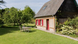 A rustic building with a sloped roof, a small window, and a door with red shutters. - La Maison des Mésanges: Private Terrace, Wi-Fi, Reversible Heat Pump, Artist's Garden (La Chapelle-sur-Dun)