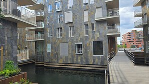 Ein mehrgeschossiges Wohngebäude mit Balkonen, einem Wasserspiel und einer Holzterrasse.