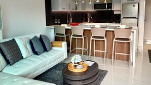 Ein modernes Wohnzimmer mit Sofa, Couchtisch und einer Küchenzeile mit Barhocker.