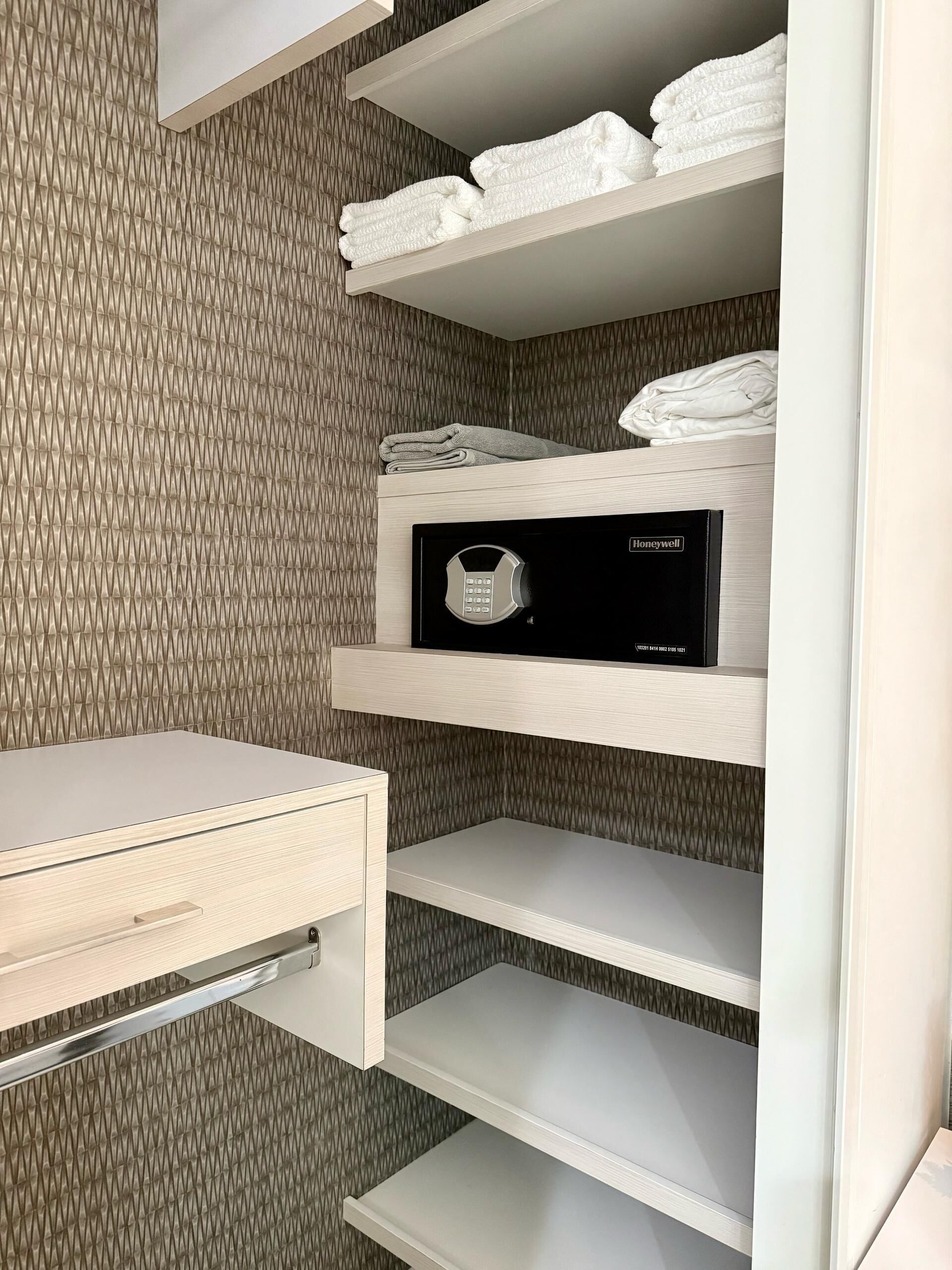 Et moderne badeværelse med et indbygget toilet, et vaskebord med spejl og en håndklædestang med pænt foldede håndklæder.