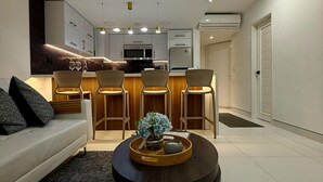 Ein modernes Wohnzimmer mit einer Couch, einem Couchtisch mit Dekoration und einer Küche im Hintergrund.
