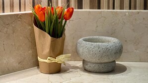 Eine Ecke mit einem Terrakotta-Blumenkasten, der orangefarbene Tulpen und einen Steintopf enthält.