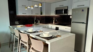 Eine moderne Küche mit Kochinsel, Edelstahlgeräten und einem Essbereich mit Tisch und Stühlen für vier Personen.