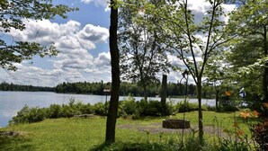 Vista sul lago con una zona erbosa, alberi e una bandiera.