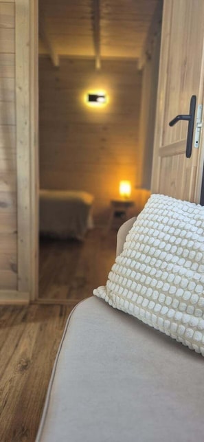 A wooden interior with a bed, a nightstand, and a door.