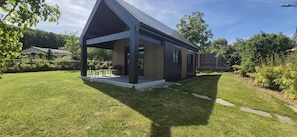 A modern house with a covered porch, a well-maintained lawn, and a clear sky.