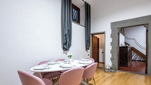 En matplats med ett runt bord dukat för sex personer, rosa stolar och en trappa i bakgrunden.