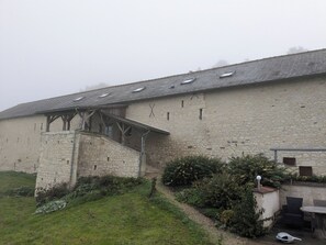 Ein Steinhaus mit geneigtem Dach und einem überdachten Eingang.