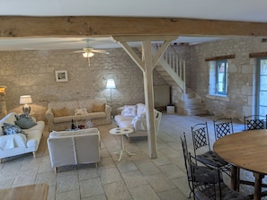 Ein geräumiges Wohnzimmer mit hohen Decken, einer Holztreppe und einem Essbereich mit einem runden Tisch.