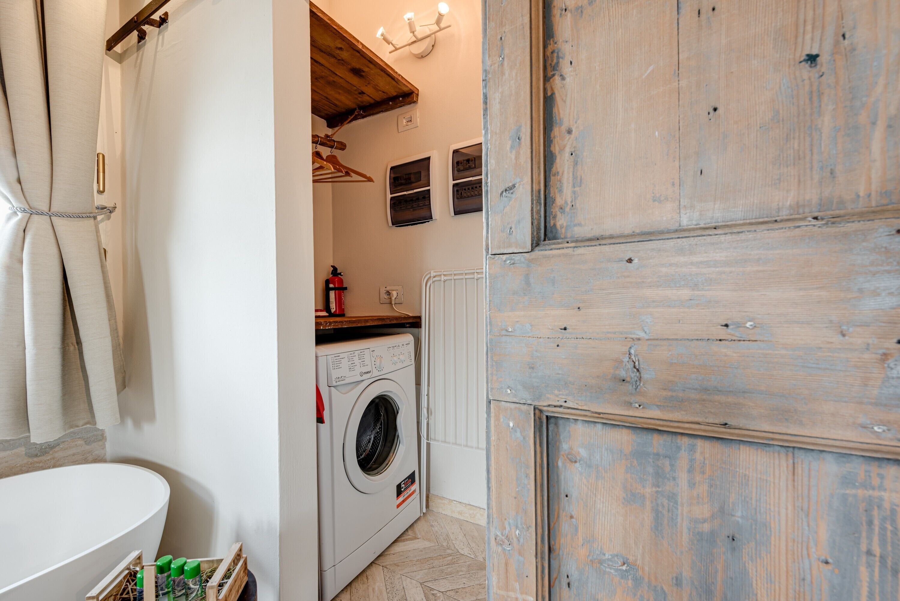A laundry area with a washing machine, a drying rack, and a wooden door.