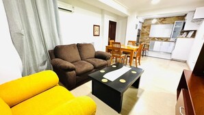 A living room with a brown sofa, yellow armchair, and a black coffee table with a white placemat.