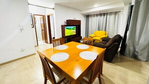 A dining area with a wooden table and chairs, a television, and a sofa.
