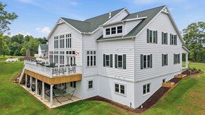 A two-story house with a deck, multiple windows, and a chimney.